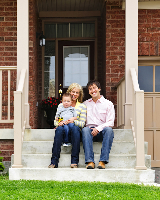 Young family sitting on front steps of house - Real Estate Law help
